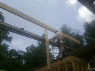 Carpenter setting a ridge beam over a new addition frame — Ice Dam Removal by Roofing Brothers in Hildebran