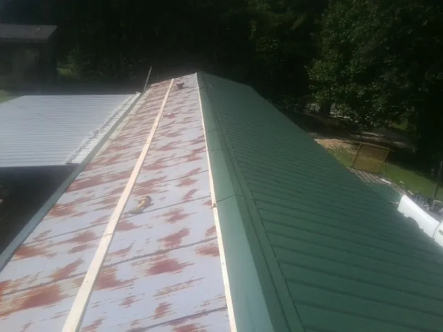 Old rusted panels beside newly installed green metal roofing — Wind Damage Roof Repair by Roofing Brothers in Hildebran