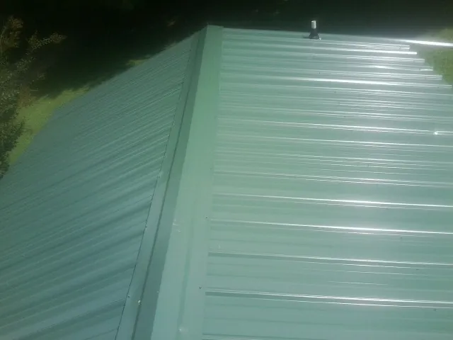 New green metal panels meeting at the ridge of a roof in Hildebran