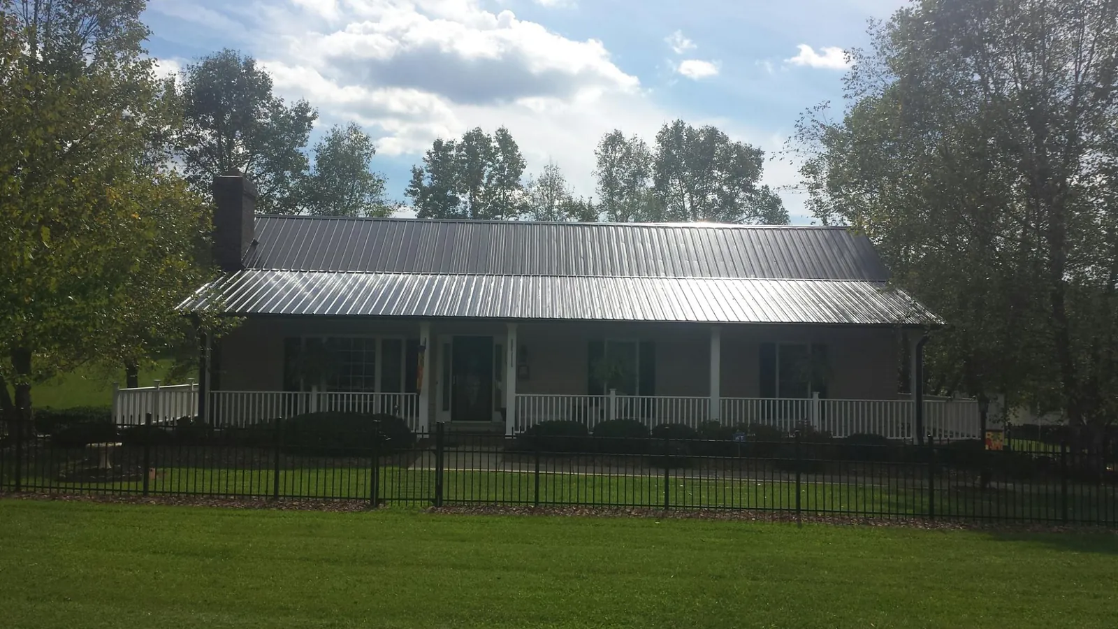 Gray metal roof on a brick ranch with a full width front porch — Gutter Guard Installation work by our crew in Hildebran