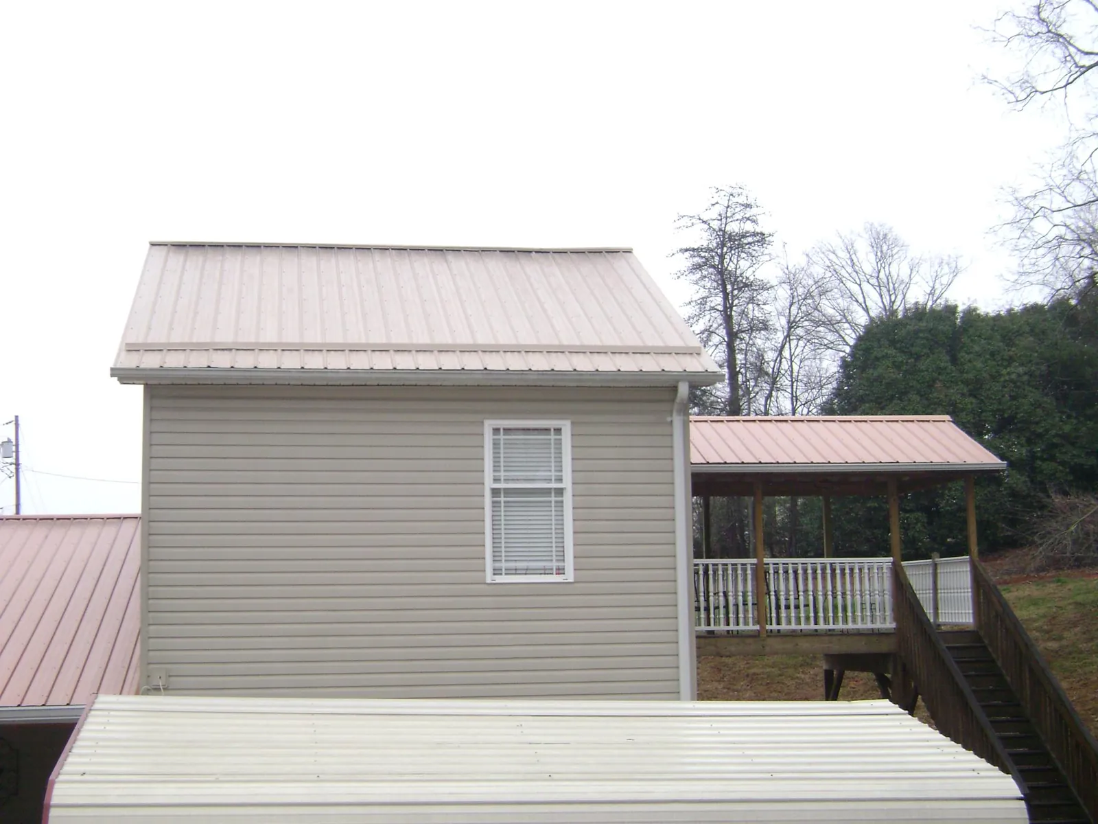 Tan metal roofs on a two story addition and attached porch, from a Roof Replacement job in Hildebran