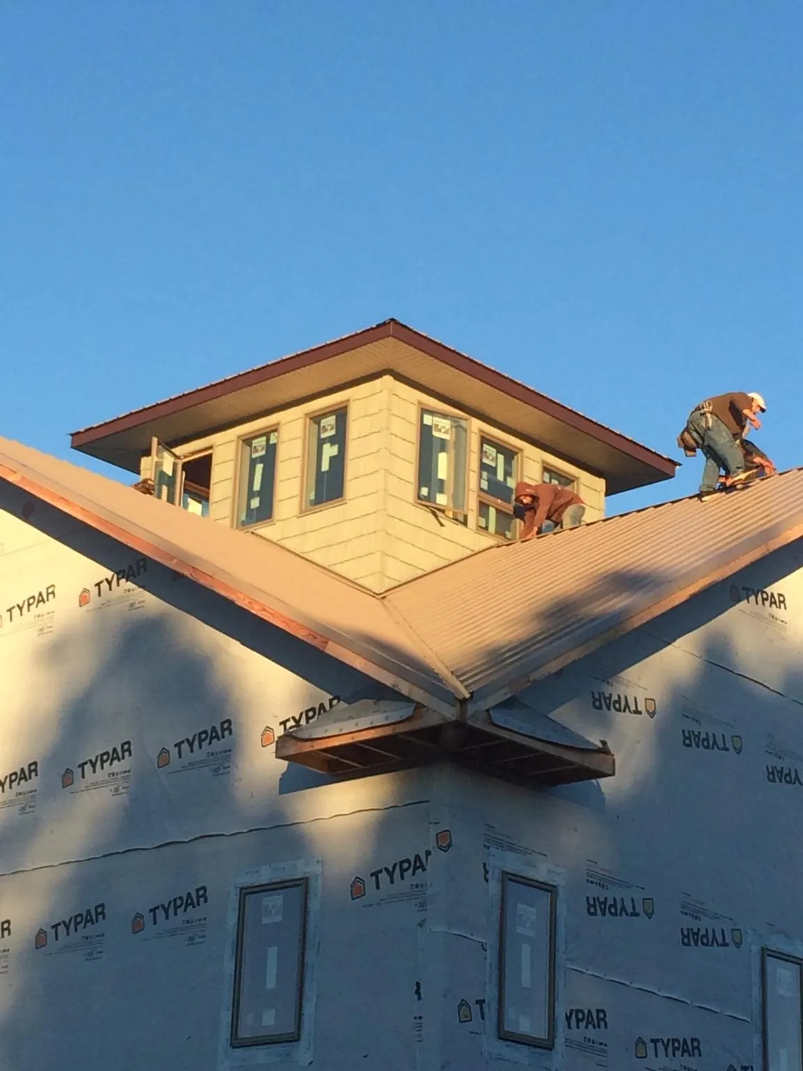 Roofers working around a rooftop cupola on a new metal roof at sunset — Roof Waterproofing in Hildebran by Roofing Brothers
